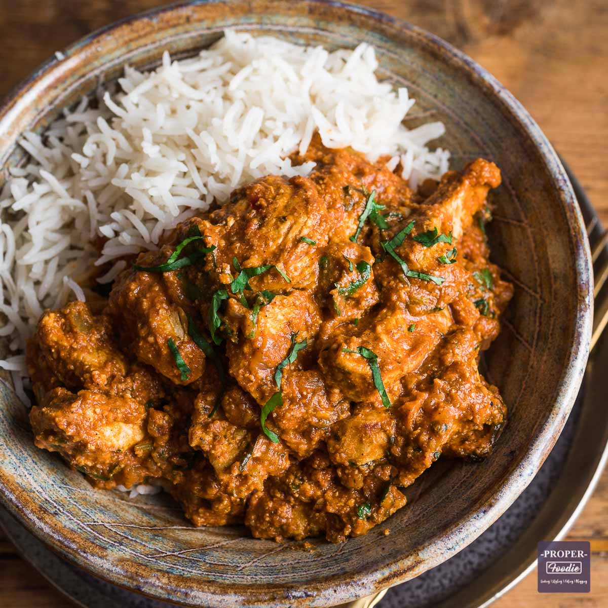 A close-up shot of a chicken curry being cooked in a pan.